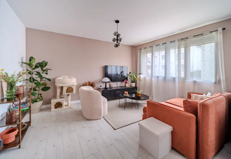 Salon moderne avec murs rose poudré et canapé orange.