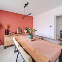 Salle à manger moderne avec mur terracotta et table en bois.