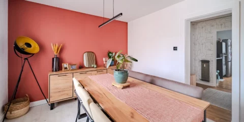 Salle à manger moderne avec mur terracotta et table en bois.