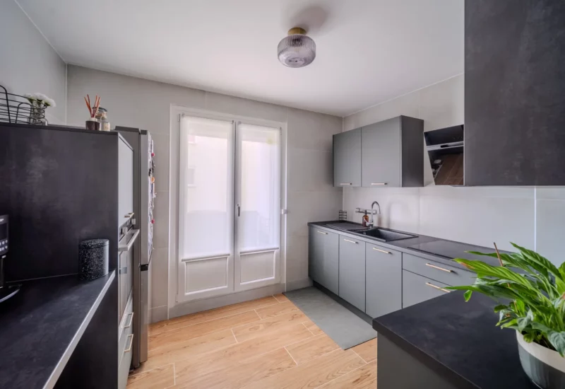 Cuisine moderne aux meubles gris et sol en bois clair.