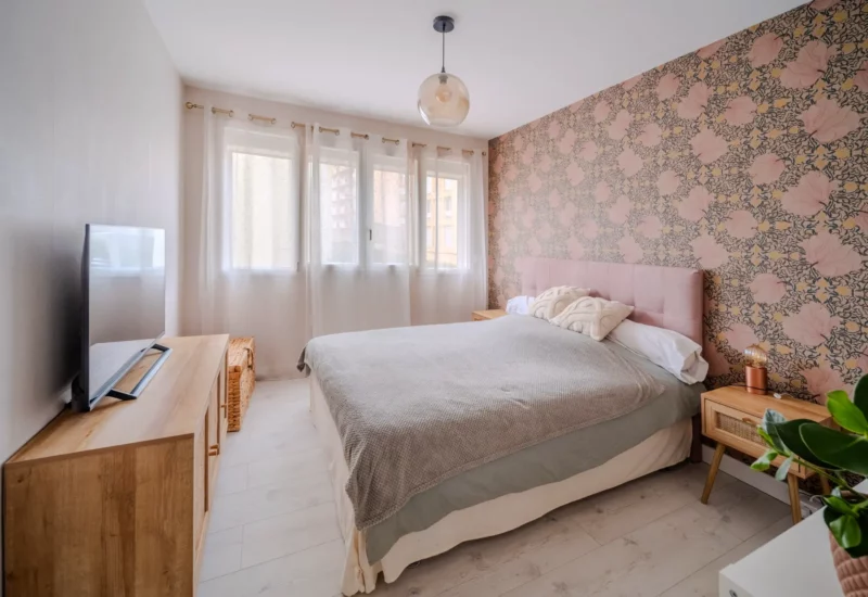 Chambre moderne avec papier peint floral rose et lit douillet.