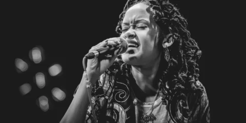 Femme chantant avec émotion dans un microphone, noir et blanc.