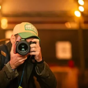 Photographe à casquette prenant une photo sous des lumières bokeh.