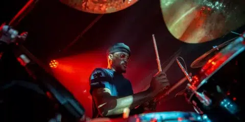 Batteur avec bonnet jouant de la batterie sous éclairage rouge.