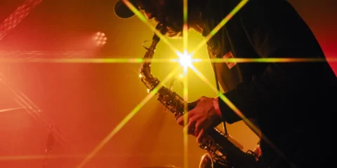Saxophoniste sur scène avec un éclat lumineux étoilé jaune.