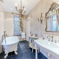 Salle de bain vintage avec baignoire sabot et miroir orné.