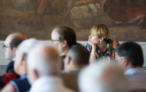 Femme pensive en chemise fleurie lors d'une assemblée.