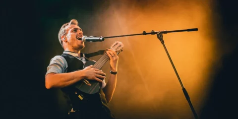 Musicien chantant et jouant du ukulélé sur scène.