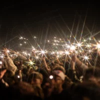 Foule nocturne tenant des téléphones allumés lors d'un concert.