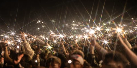 Foule nocturne tenant des téléphones allumés lors d'un concert.
