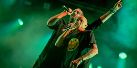 Deux chanteurs de rap sur scène sous lumière verte.