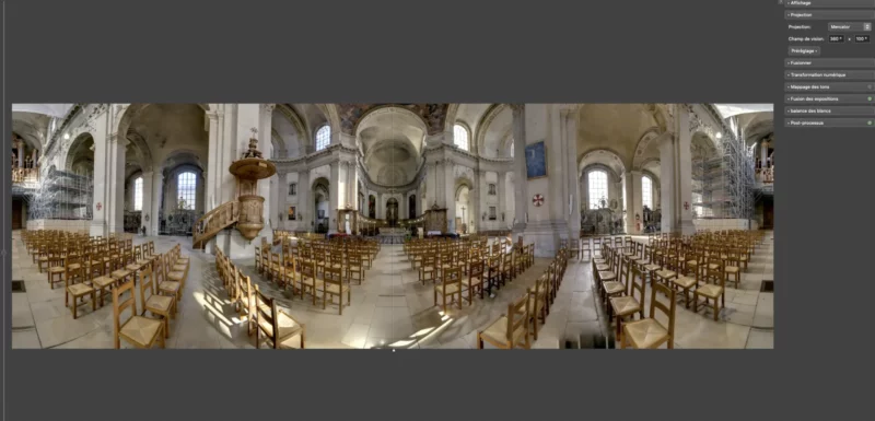 Vue panoramique intérieure d'une église avec des chaises alignées.